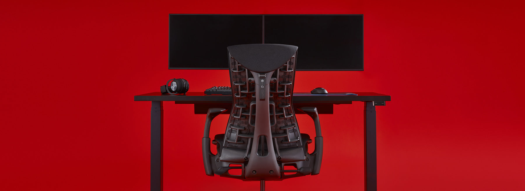 A black Embody Gaming Chair and Nevi Gaming Desk with a dual monitor setup supported by Ollin Monitor Arms.